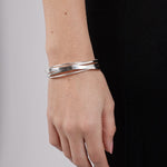 Silver bracelet on a wrist with a plain background