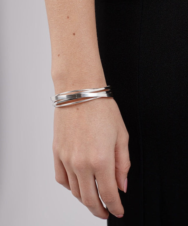 Silver bracelet on a wrist with a plain background