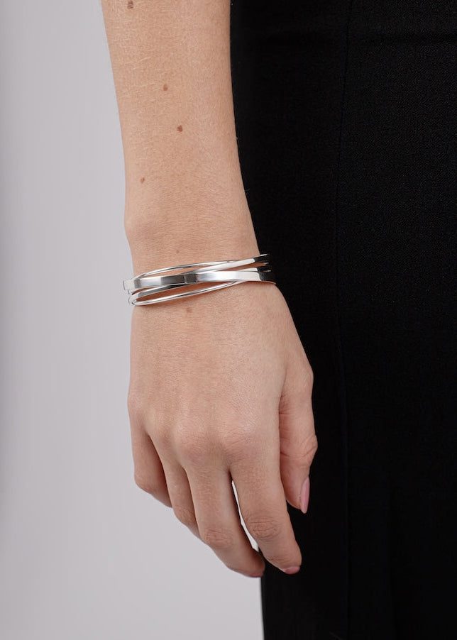 Silver bracelet on a wrist with a plain background