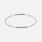 A thin, polished silver bangle bracelet with a subtle hammered or textured finish, shown against a solid light gray background.