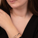 Woman wearing a silver bracelet on her wrist with a neutral background