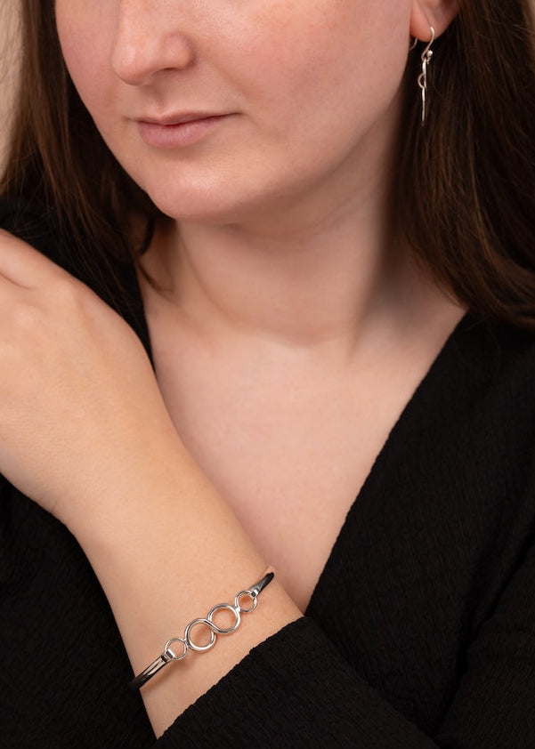 Woman wearing a silver bracelet on her wrist with a neutral background
