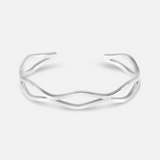Silver bracelet with a branch-like design on a white background