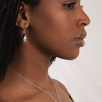 Woman wearing a necklace and earring against a white background