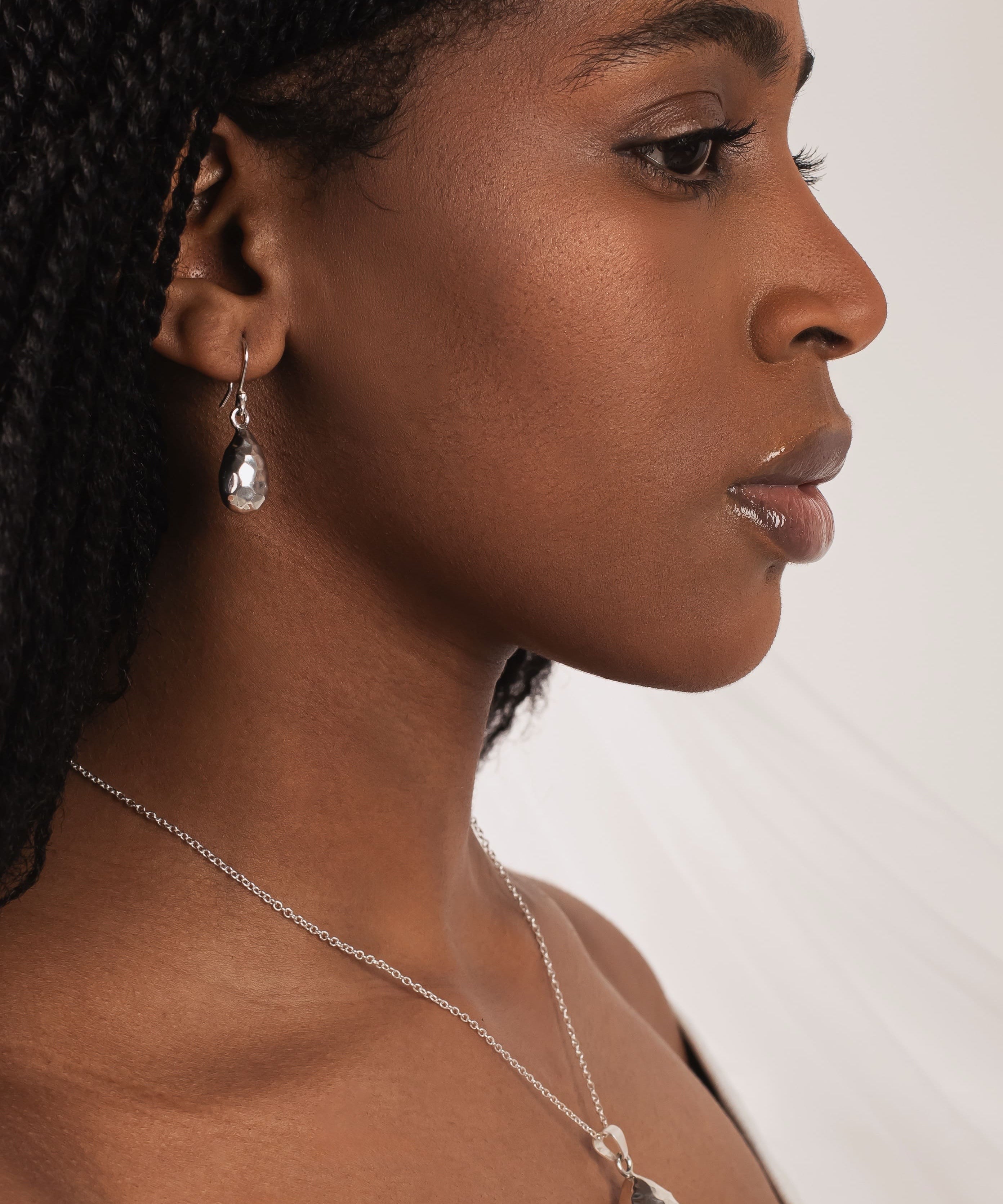 Woman wearing a necklace and earring against a white background