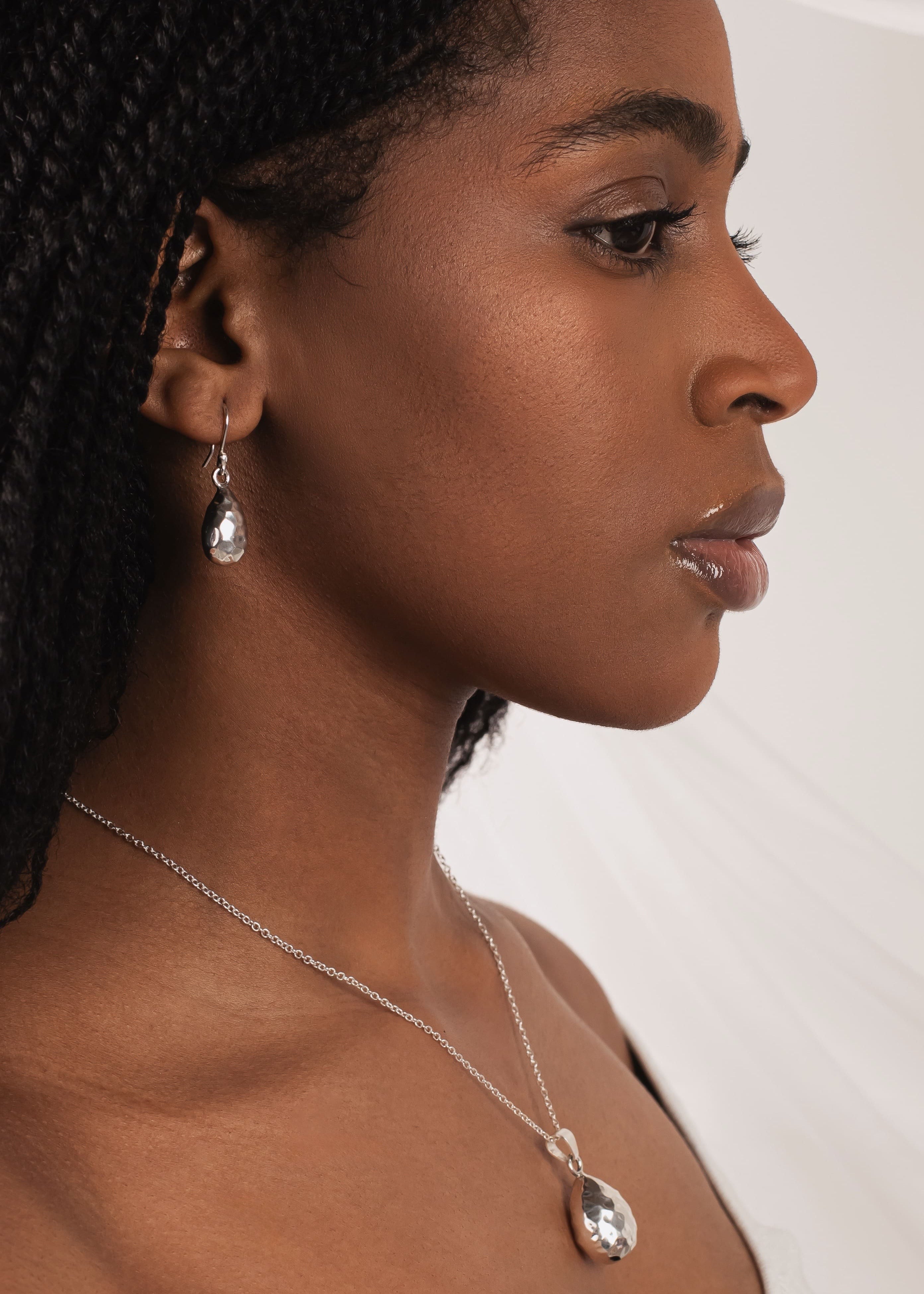 Woman wearing a necklace and earring against a white background