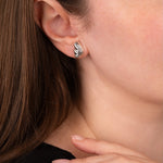 Close-up of a person wearing silver hoop earrings with a blurred background