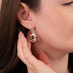 Close-up of a woman wearing a silver earring with a pink gemstone.