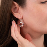 Close-up of a woman wearing a silver earring with a pink gemstone.