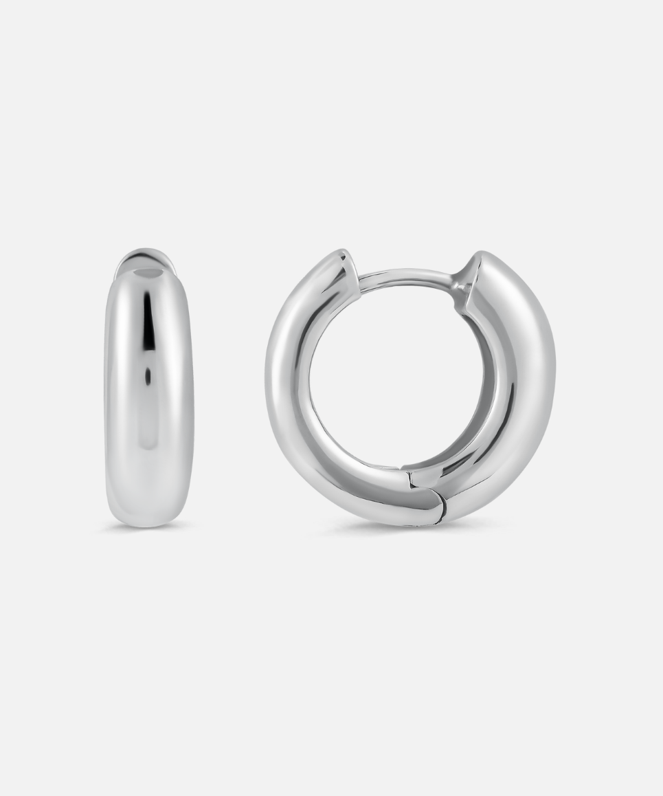 A pair of chunky hoop earrings made of silver metal, displayed against a white background.