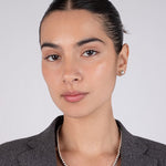 Woman wearing a gray blazer and silver necklace against a plain background