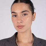 Woman wearing a gray blazer and silver necklace against a plain background