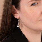 Close-up of a woman wearing silver earrings with a neutral background
