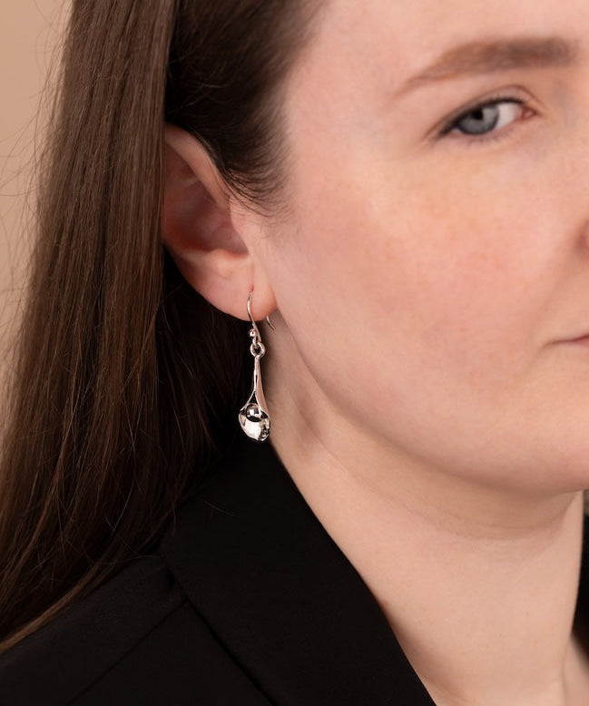 Close-up of a woman wearing silver earrings with a neutral background