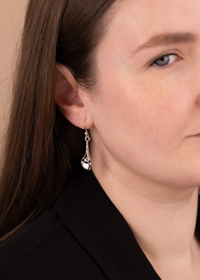 Close-up of a woman wearing silver earrings with a neutral background
