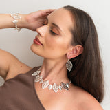 Woman wearing jewelry including earrings and a necklace against a plain background