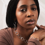 Woman wearing a brown top and silver jewelry against a white background