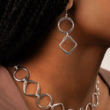 Silver necklace and earrings on a person wearing a black headscarf.