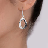Silver teardrop earring worn by a person with a neutral background