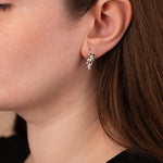Close-up of a person wearing a silver earring with a leaf design.
