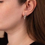 Close-up of a person wearing a silver earring with a leaf design.