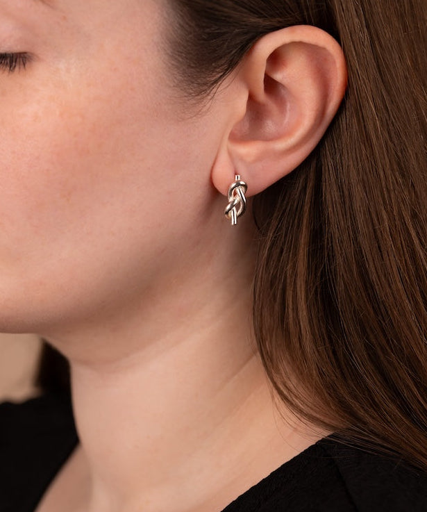 Close-up of a person wearing a silver earring with a leaf design.