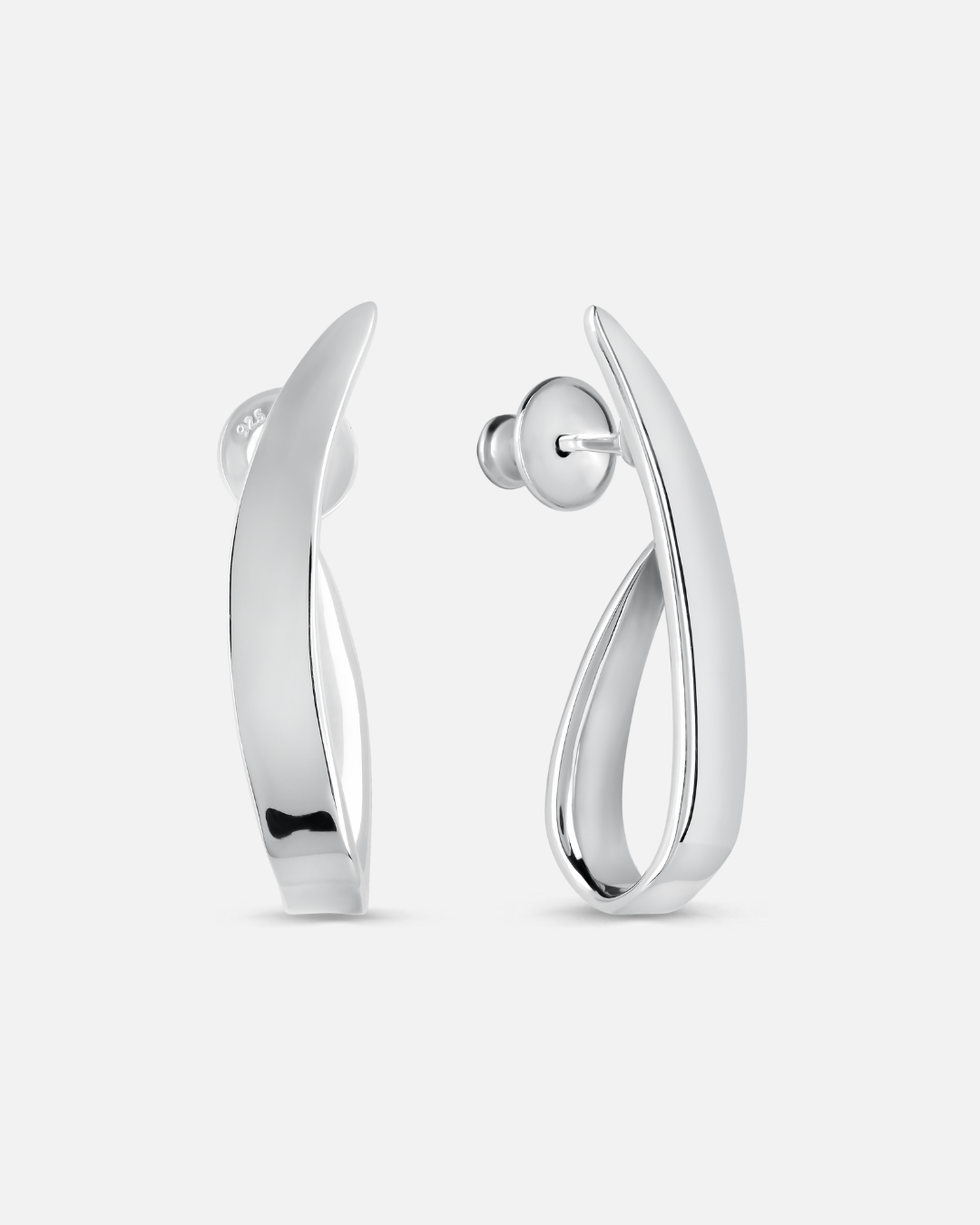 A pair of polished silver huggie hoop earrings with a modern, fluid curved design, shown from both front and side angles on a light gray background.