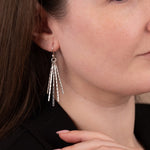 Close-up of a woman wearing silver earrings with a neutral background