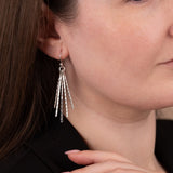 Close-up of a woman wearing silver earrings with a neutral background