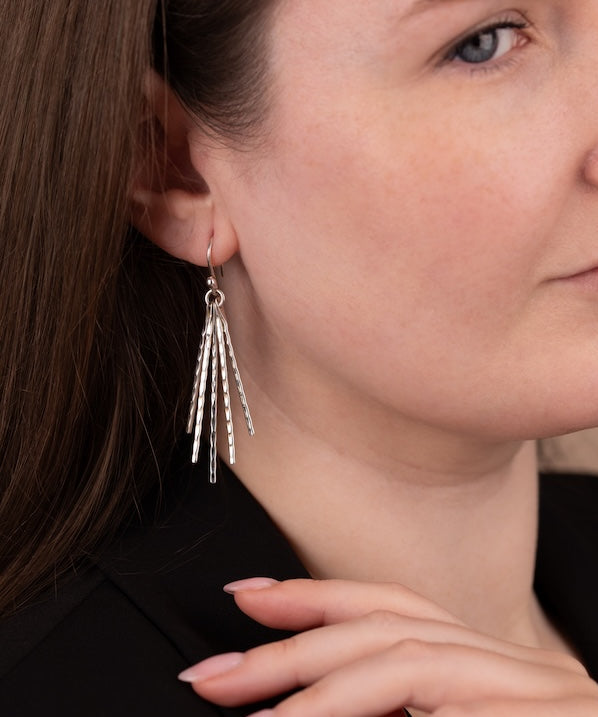 Close-up of a woman wearing silver earrings with a neutral background