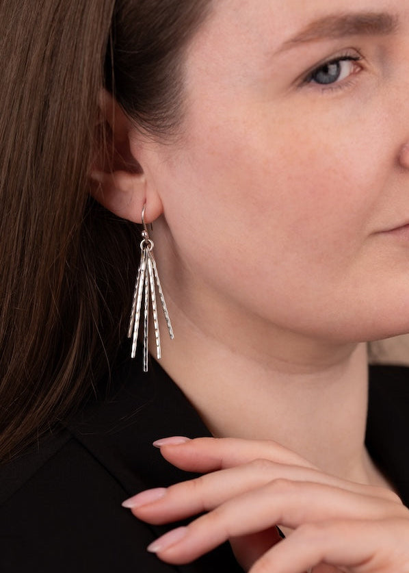 Close-up of a woman wearing silver earrings with a neutral background