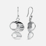 A pair of silver drop earrings with organic, abstract oval and teardrop shapes, featuring textured and polished finishes, shown against a light gray background.