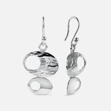 A pair of silver drop earrings with organic, abstract oval and teardrop shapes, featuring textured and polished finishes, shown against a light gray background.