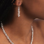 Close-up of a woman wearing a silver necklace and earrings.