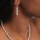 Close-up of a woman wearing a silver necklace and earrings.