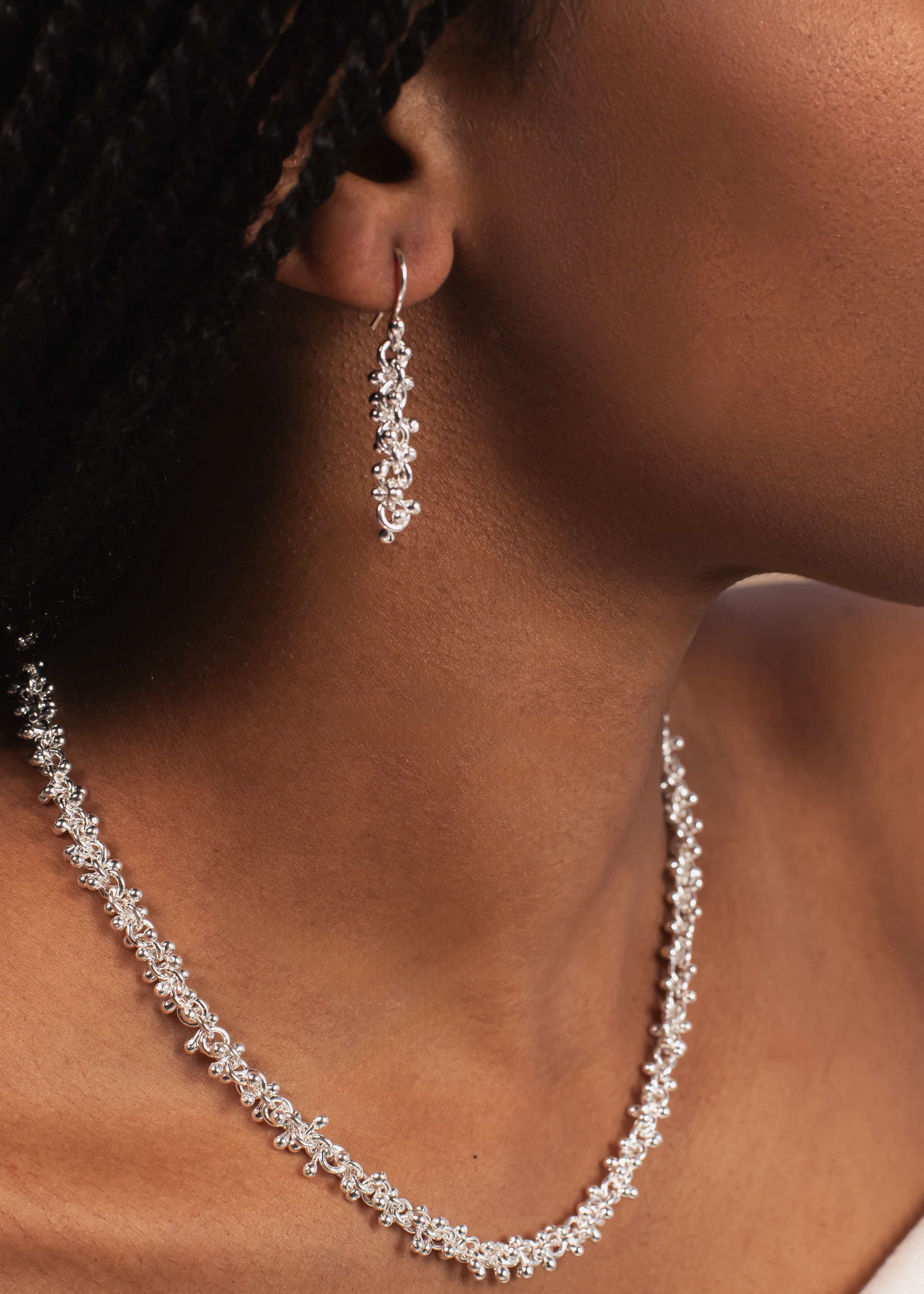 Close-up of a woman wearing a silver necklace and earrings.