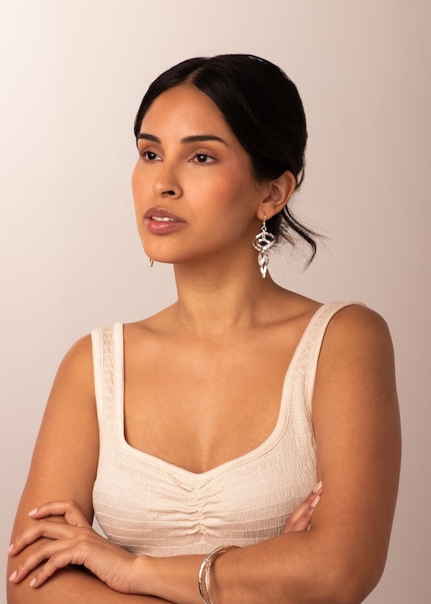 Woman wearing a beige sleeveless top against a plain background