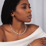 Woman wearing a white off-shoulder top and jewelry against a plain background