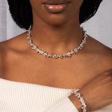 Woman wearing a silver necklace and bracelet against a neutral background
