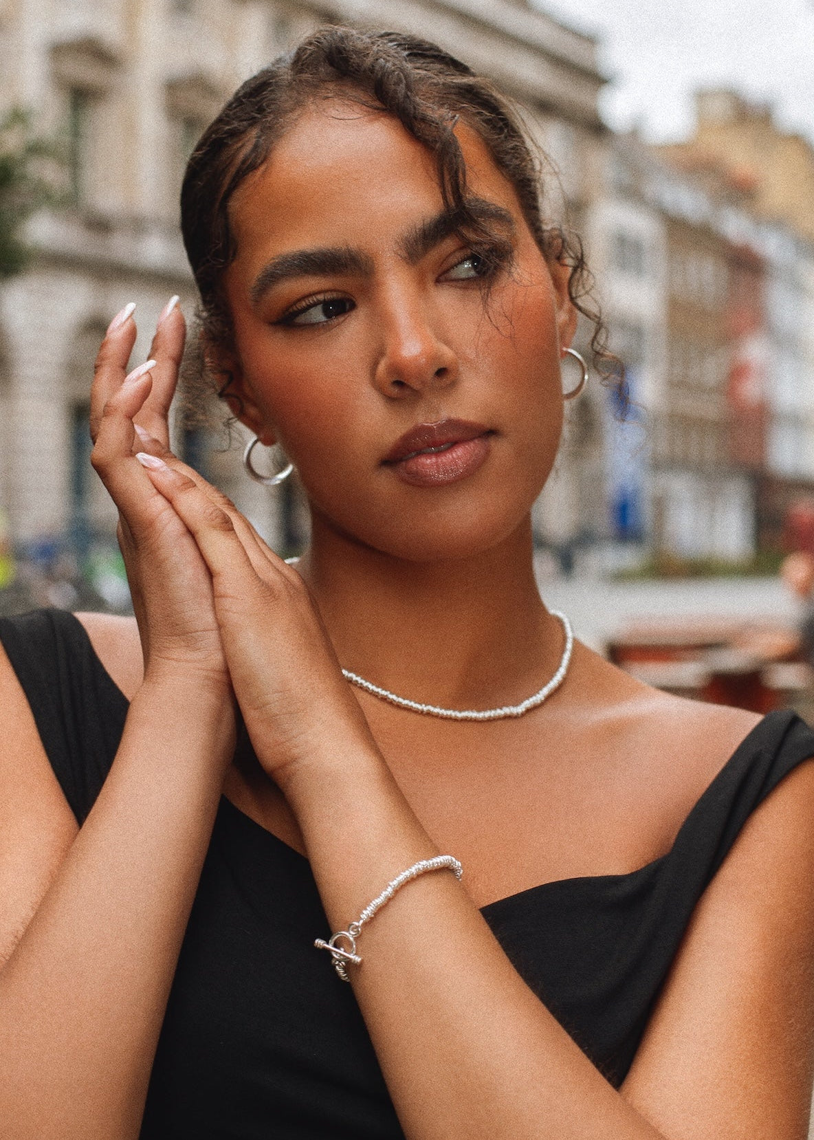 Woman wearing a black dress with jewelry in an urban setting