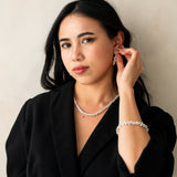 Woman wearing a black blazer and jewelry against a plain background
