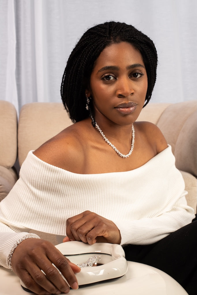 Woman sitting on a couch holding a jewelry box with a ring inside.