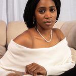 Woman sitting on a couch holding a jewelry box with a ring inside.